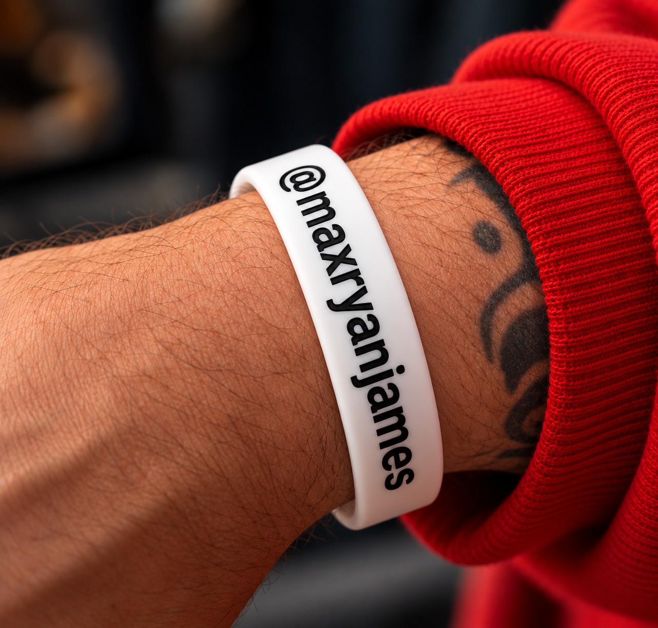 White silicone wristband printed with @maxryanjames in black, worn on a wrist